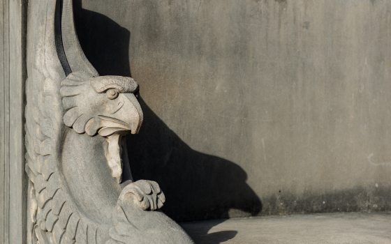 The end of a stone bench with a carved head of an eagle in it.